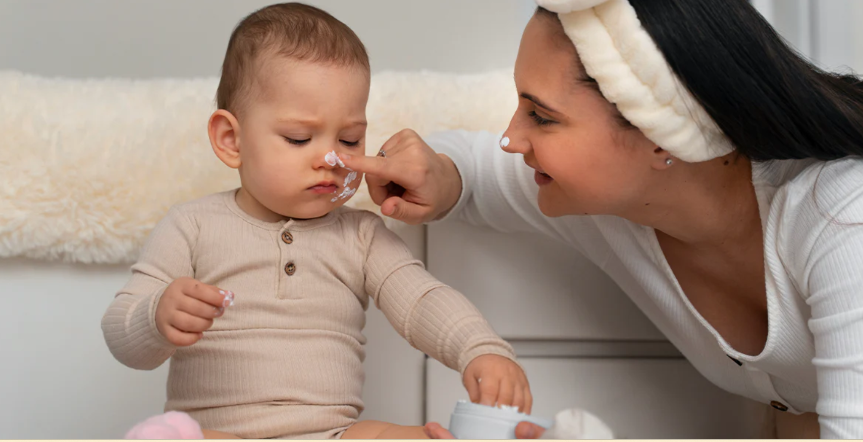 mamá poniendole crema en la cara a bebé